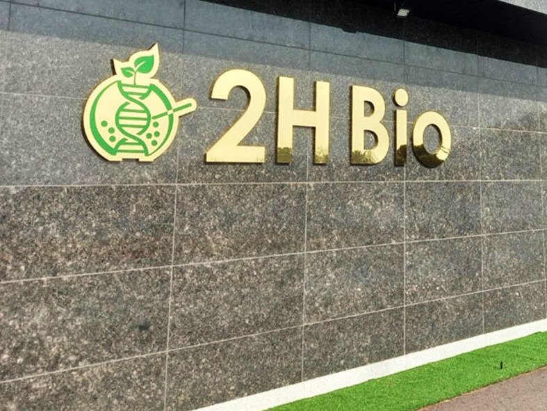 회색 석재 외벽에 금색 2H Bio 로고 간판이 달린 사옥 건물